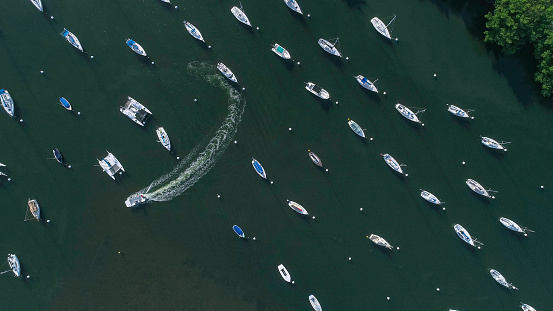 A large group of boats anchored along the coast, in rows, in shallow water of a tropical place. Aerial view (directly from above).