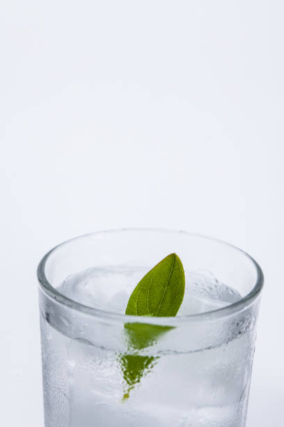istock Glass of cold ice water with green leaf on white background 1003834248