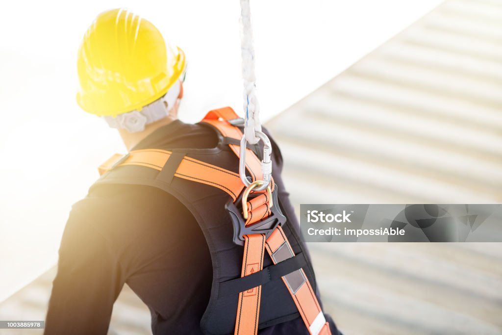 Industrial Worker with safety protective equipment loop and harness hanging at his back safety in factory concept Safety Harness Stock Photo