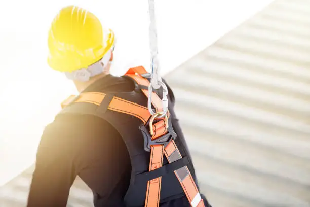 Photo of Industrial Worker with safety protective equipment loop and harness hanging at his back