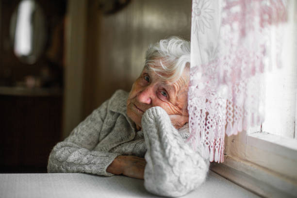 istock Sad old woman sitting near the window. 1003892954
