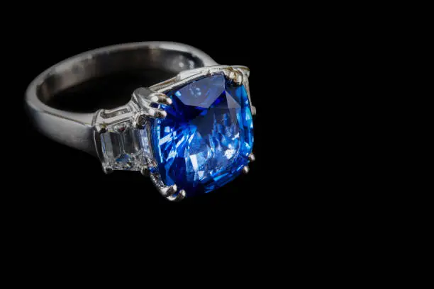 Ring of the jewelry with dark blue sapphire on the black background