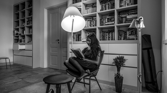 Young woman reading book at home.