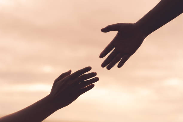 istock helping hands on blurred sea and sky background. Friendship Day concept. 1003909856