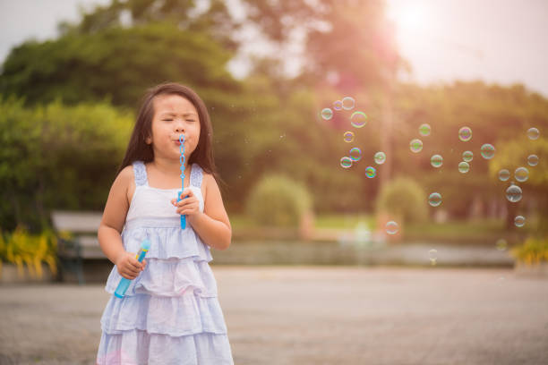 istock Cute little girl having fun with blowing soap bubbles in summer park. 1003912502