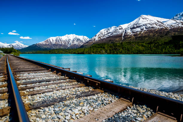 istock Railroad track with lake and mountain range 1003912652