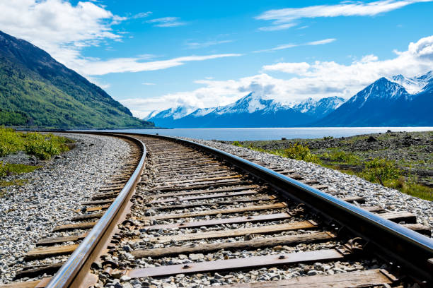 Railroad track with mountain range and fjord Part of Alaska railroad in the Chugach National Forest with mountain range and Turnagain arm in background. chugach national forest photos stock pictures, royalty-free photos & images