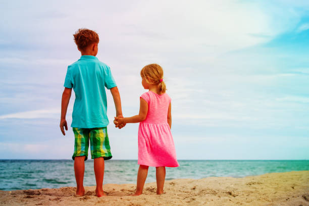 istock little boy and girl walk on summer beach 1003915618