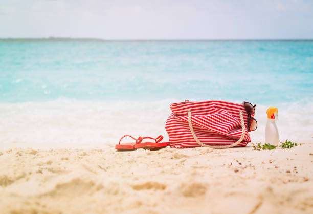 istock Beach bag, flip-flop and suncream on beach 1003918484