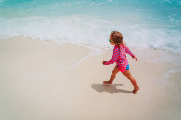 istock little girl run play with waves on the beach 1003918598