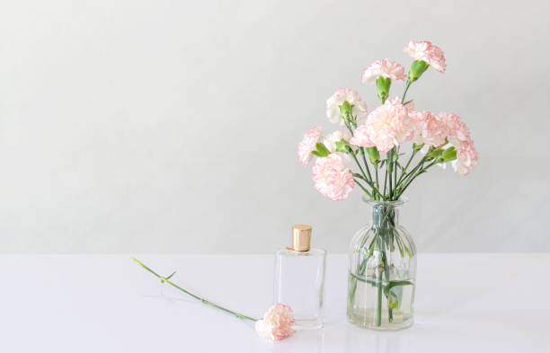 istock perfume bottle with carnation flowers vase on white table. 1003920994