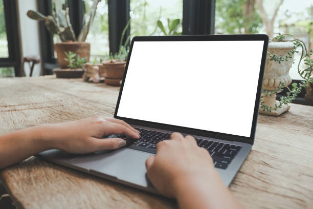 istock Mockup image of hands using and typing on laptop with blank white desktop screen on vintage wooden table in cafe 1003944890