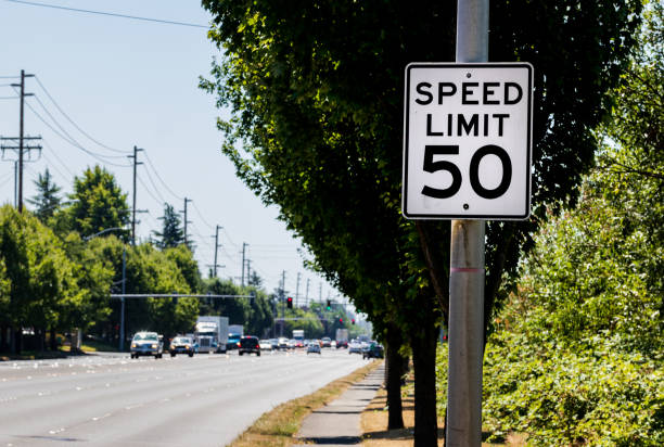 istock 50 mph speed limit sign on post with a road and tree 1003954054