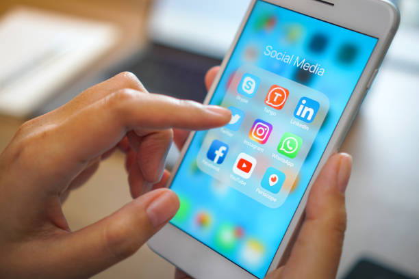 социальные медиальные приложения iphone мобильный телефон с синим экраном фон технологии бизнес смартфон цифровой связи facebook и интернет-реда - социальный сбор стоковые фото и изображения