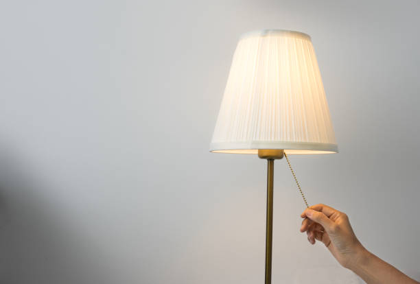 istock Female hand switch on table lamp. 1003979858