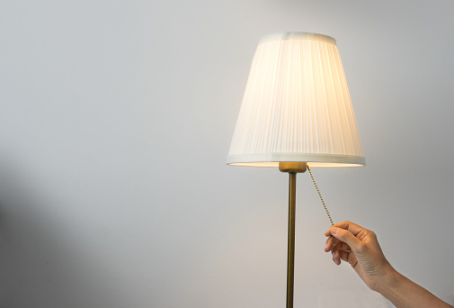 Woman hand switch on table lamp.