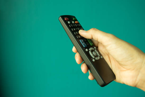istock TV remote control in female hand. 1003979872