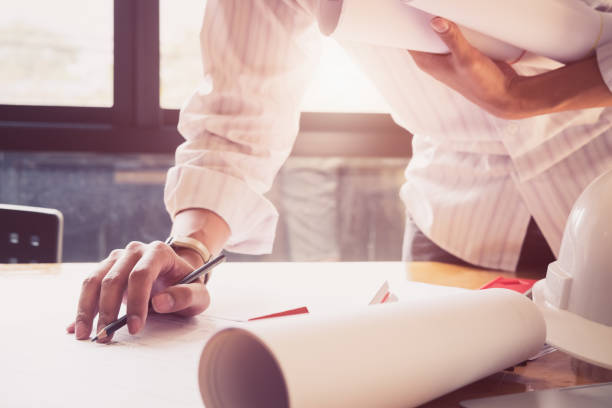 istock Architect or engineer working in office with blueprints,engineer inspection in workplace for architectural plan,sketching a construction project ,selective focus,Business construction concept. 1003986694
