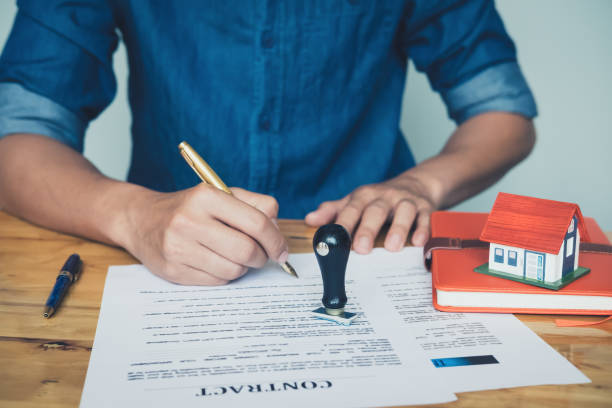 istock Rubber stamp put on the table between real estate agent holding house to his client after signing contract,concept for real estate,insurance with house, moving home or renting property 1003986730