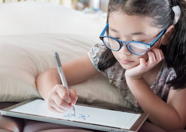 istock Asian school child girl using smart  tablet device digital technology drawing on innovative touchscreen surface 1003989200