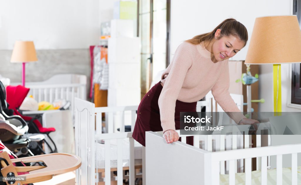 woman buyer choosing wooden crib woman buyer choosing wooden crib in the shop of furniture for baby Crib Stock Photo