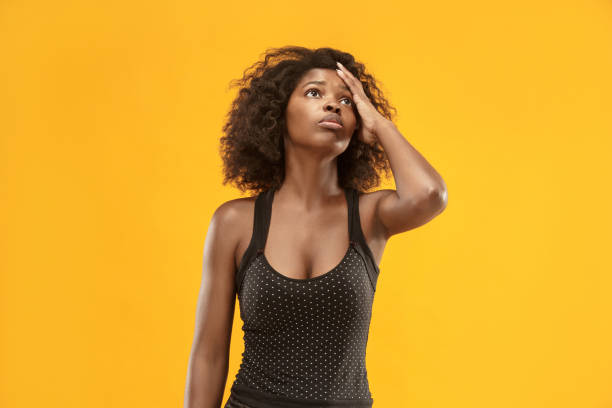 istock Woman having headache. Isolated over gold background 1003994436