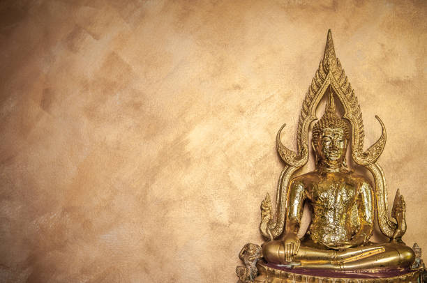 istock Gold leaves on Buddha Sculpture on gold wall background 1003994546