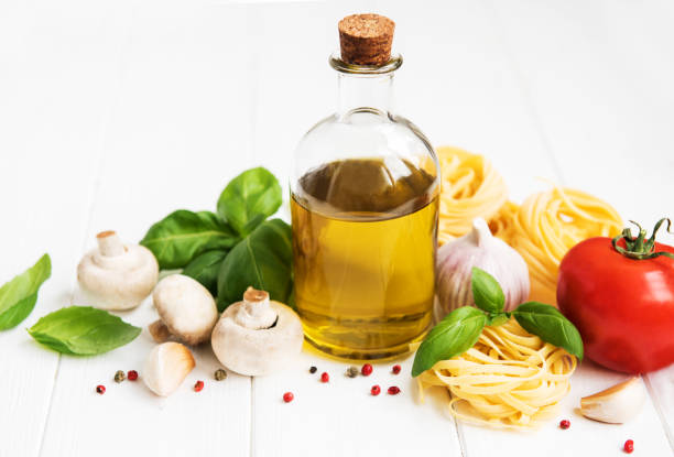 Italian food ingredients, olive oil, spices, pasta and tomatoes on a white wooden table