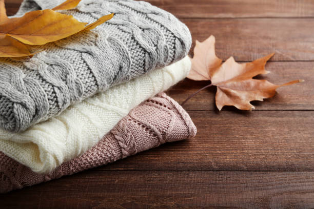 istock Stack of knitted sweaters with autumn leafs on wooden table 1004030094