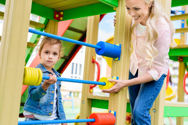 istock smiling mother teaching to count little daughter on abacus at playground 1004039920