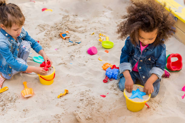 istock high angle view of two little multicultural children using plastic molds in sandbox at playground 1004040922