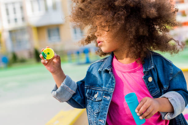 istock curly african american little child playing with soap bubbles 1004040938
