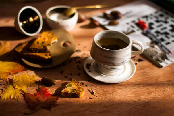 autumn still life, cup of tea on the table and autumn leaves. The sun is shining