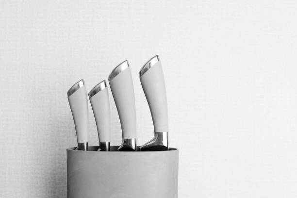 Set of metallic knives in holder in black and white stock photo
