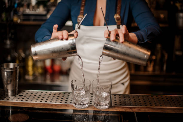 istock Barmaid pouring fresh summer cocktail from shakers into glasses 1004056726