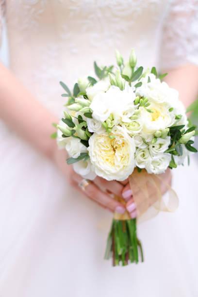 istock Closeup bride keeping white bouquet of flowers 1004068712