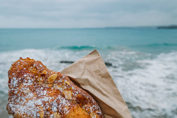 istock Hand holding an Almond Croissant, Newquay, Cornwall. 1004070698