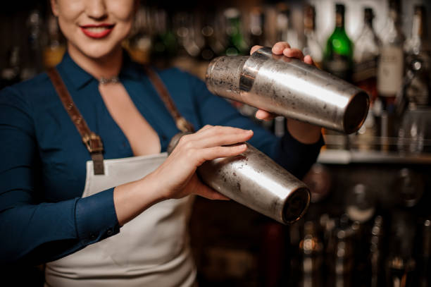 istock Beautiful smiling sexy barmaid making cocktail in a shaker 1004073622