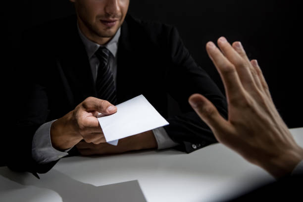 istock Businessman rejecting money in white envelope offered by his partner in shadow 1004108408