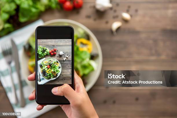 Hand Holding Smartphone Taking Photo Of Beautiful Food Mix Fresh Green Salad Stock Photo - Download Image Now