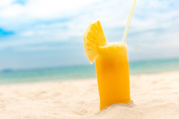Glass of refreshing tropical pieapple fruit juice smoothie drink in summer beach background