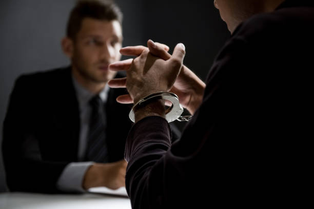 istock Criminal man with handcuffs being interviewed in interrogation room 1004108906