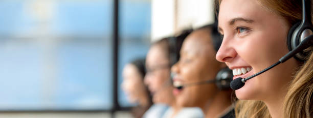 Woman customer service agents working in call center Friendly beautiful caucasian woman telemarketing customer service agent working in call center with multiethnic team customer service representative photos stock pictures, royalty-free photos & images