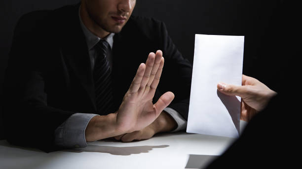 istock Businessman rejecting money in white envelope offered by his partner in shadow 1004108920