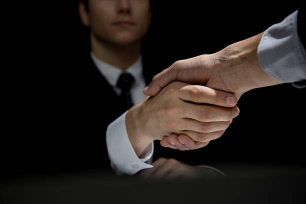 Business partners making handshake in dark shadow