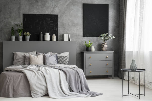istock Moon canvas on a grey wall in a monochromatic cozy bedroom interior with a bed with cushions, bedding an a blanket. Real photo 1004109112
