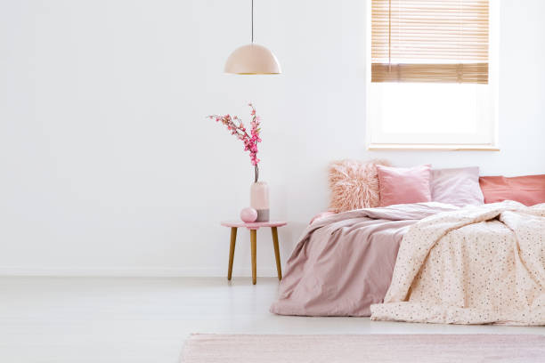 lámpara de sobre mesa con flores en interior de color rosa pastel dormitorio con ventana por encima de la cama. foto real - decor indoors pillow bedroom fotografías e imágenes de stock