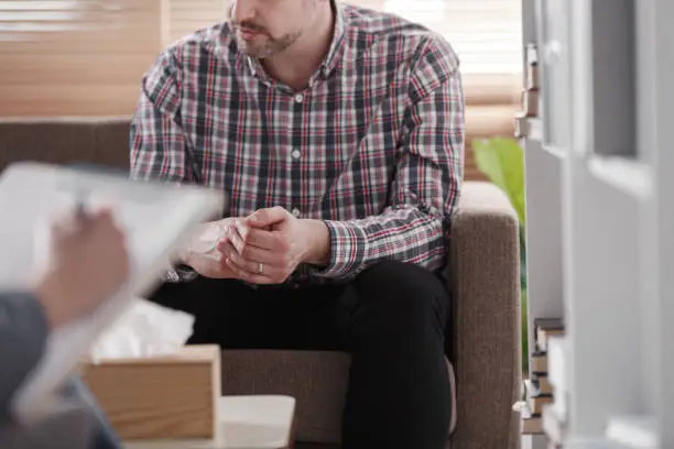 Photo of Close-up of a man sitting on a couch during marital consultation in an office