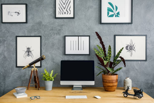 istock Plants, telescope and computer desktop on wooden desk in work area interior with posters. Real photo 1004109322