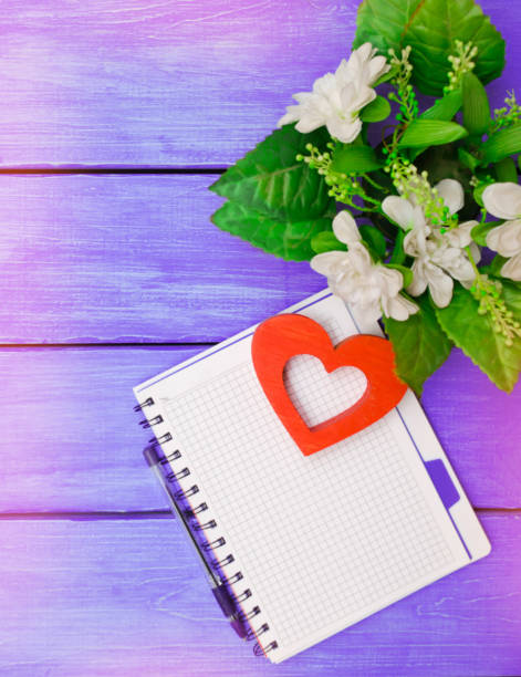 istock spring, notebook with pen, flowers, on a purple wooden background 1004117236
